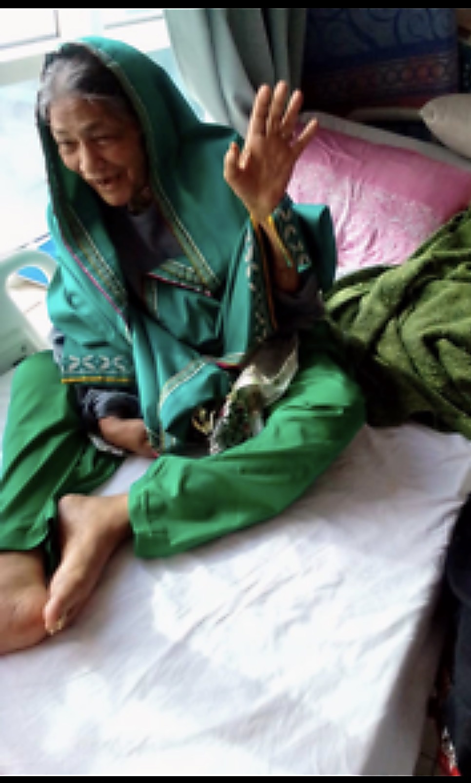 An elderly woman living with advanced Alzheimer's disease, smiling, her hand raised